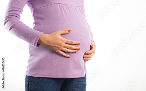 The belly of a pregnant girl which she holds with her hands on a white background, isolate. Abdominal bloating in pregnant women awaiting the birth of a child, close-up