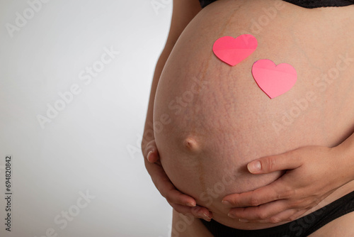 Wallpaper Mural Pregnant girl with a big belly and pink hearts on a white background. The concept of love and motherhood for future children. Copy space for text. Preparation for childbirth Torontodigital.ca