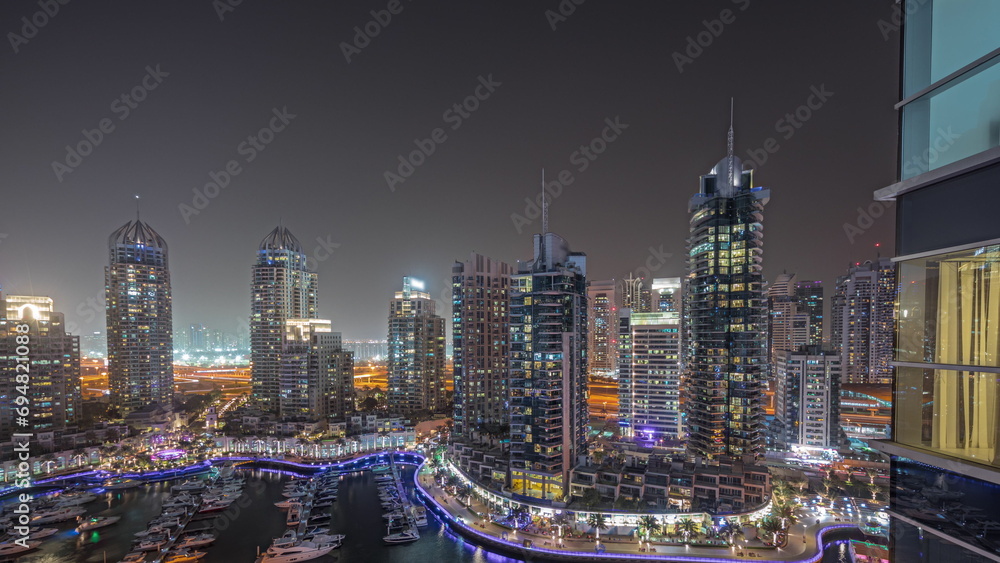 Fototapeta premium Panorama showing Dubai marina tallest skyscrapers and yachts in harbor aerial night timelapse.