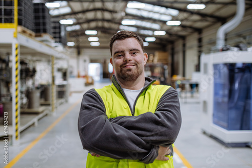 Portrait of young man with Down syndrome working in warehouse. Concept of workers with disabilities, support in workplace. photo