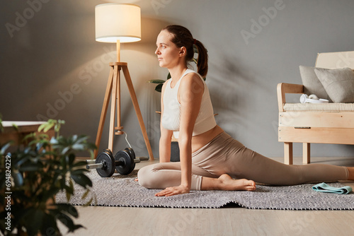 Active aerobics at home. Stretching in sportswear. Weight workout for fitness. Sporty woman in sportswear doing fitness stretching exercises at home in the living room photo
