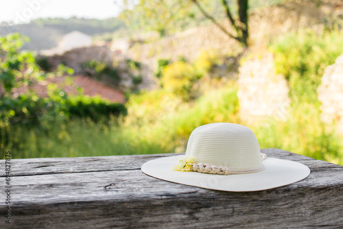 Fototapeta Naklejka Na Ścianę i Meble -  Summer nature background. Braided straw hat on bench in garden. spring season. Rustic composition nature. Relax voyage time. Copy space and mock up place for text