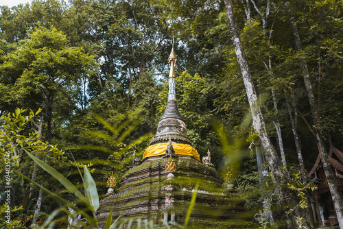 Ancient Buddhist temple in green forest during daytime in Thailand photo