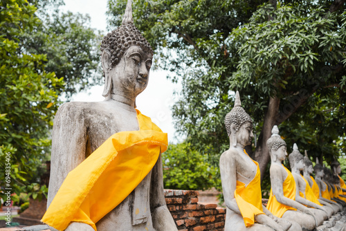 Stone Buddha statues covered with yellow cloth in Thailand photo