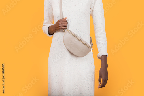 Anonymous fashionable black woman in sling bag isolated on yellow background photo