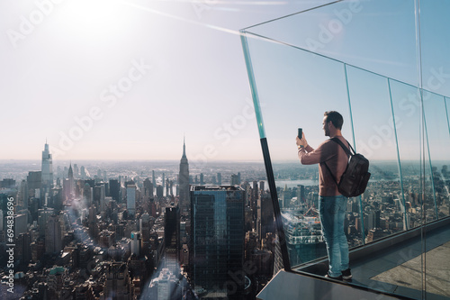 Man photographing Manhattan cityscape in sunlight photo