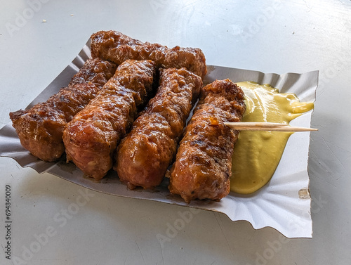 Obraz na płótnie Mici with mustard and a toothpick on a paper plate. Traditional romanian fast food. w salonie