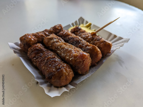 Obraz na płótnie Mici with mustard and a toothpick on a paper plate. Traditional romanian fast food. w salonie