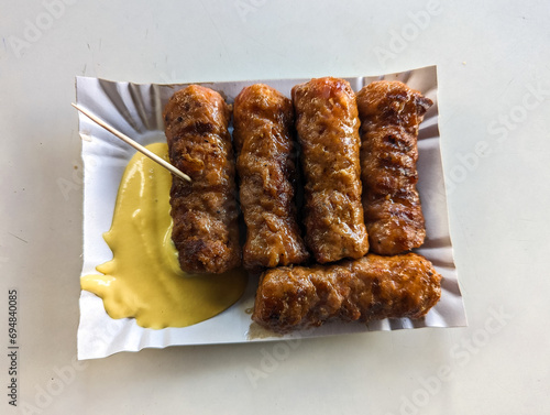 Obraz na płótnie Mici with mustard and a toothpick on a paper plate. Traditional romanian fast food. w salonie
