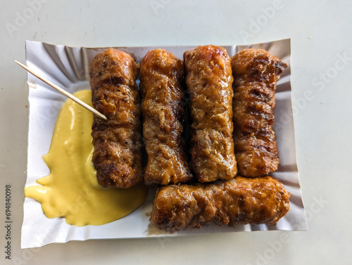 Obraz na płótnie Mici with mustard and a toothpick on a paper plate. Traditional romanian fast food. w salonie