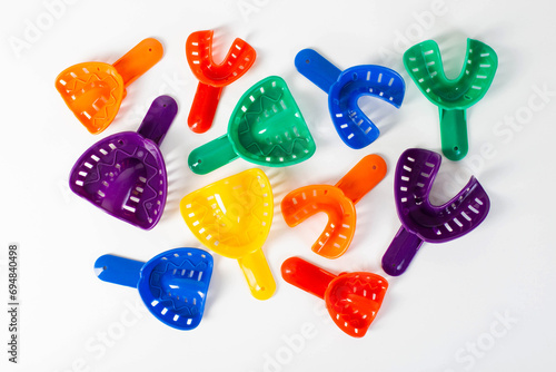 Multi-colored dental spoons for taking an impression of the dental jaw on a white background. Orthodontics in dentistry. photo