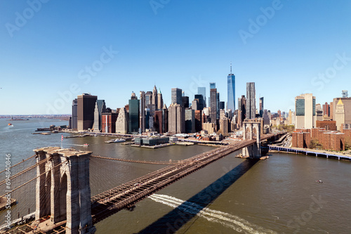 Brooklyn Bridge with city skyline backdrop under blue sky. photo