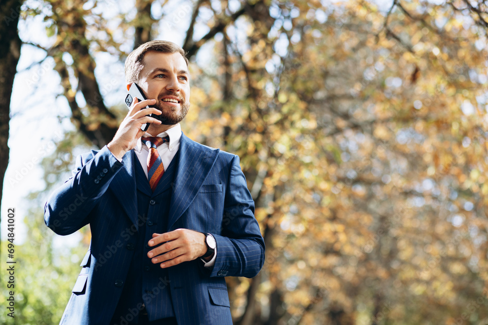 Business man talking on the phone and walking in park Business man talking on the phone and walking in park