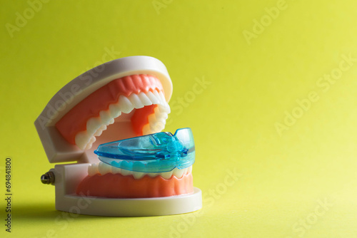 Dental mouth guard for bruxism with a mock-up of a dental jaw on a yellow background. Concept for treatment and protection of teeth from grinding during sleep in children. 