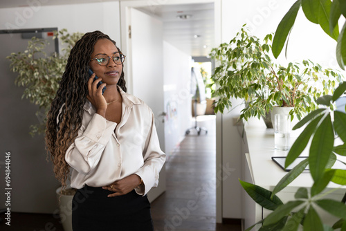 Thoughtful black businesswoman using smartphone in office