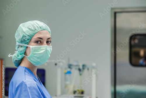 Female surgeon in uniform with medical mask and cap standing at hospital photo