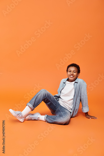 cheerful preadolescent african american boy sitting on floor and smiling happily at camera © LIGHTFIELD STUDIOS