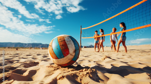 Ball Covered In Sand Is Laying Near The Volleyball Net At the Beach photo