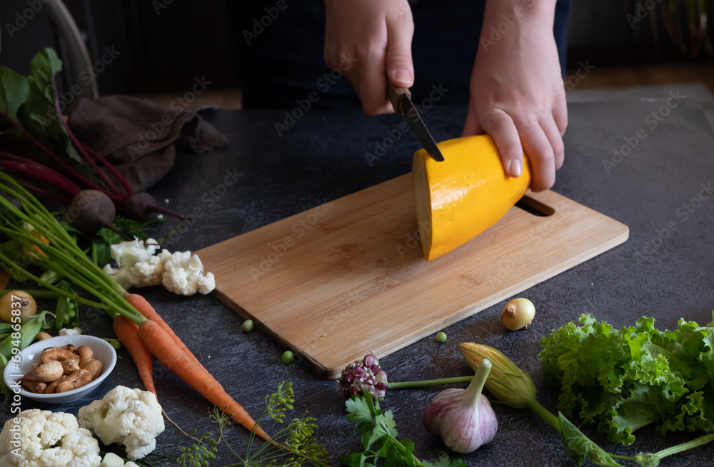 Close up of young woman hands cutting zucchini on wooden cutting board at home. Young woman preparing healthy food. Close up of young woman hands cutting zucchini on wooden cutting board at home. Young woman preparing healthy food.