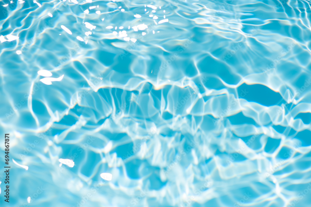 Bluewater waves on the surface ripples blurred. Defocus blurred transparent blue colored clear calm water surface texture with splash and bubbles. Water waves with shining pattern texture background.