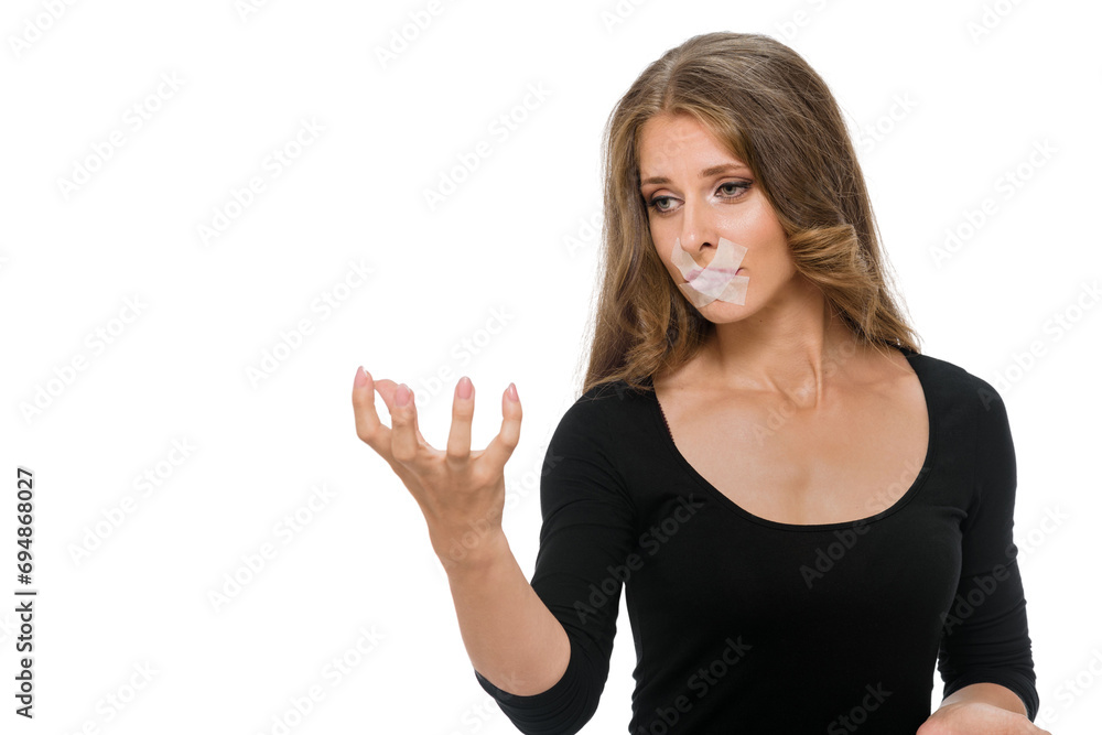 Young attractive sad girl with duct tape on her mouth and outstretched hand posing on a studio background, the concept of proper food Young attractive sad girl with duct tape on her mouth and outstretched hand posing on a studio background, the concept of proper food