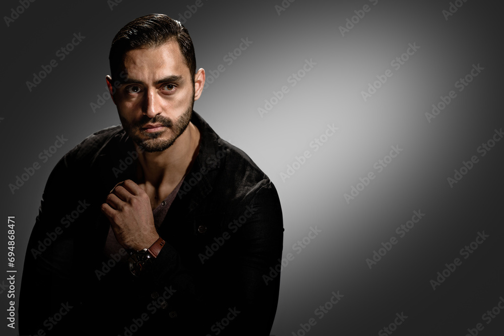 Handsome man with serious face and brutal style posing on dark background, Dark intensity: A young man's serious portrait with a hint of brutality