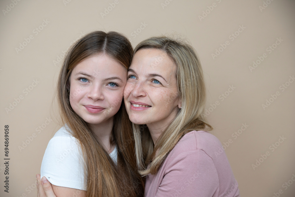 beautiful young, teenager girl together with her beautiful mother posing in front of brown background beautiful young, teenager girl together with her beautiful mother posing in front of brown background