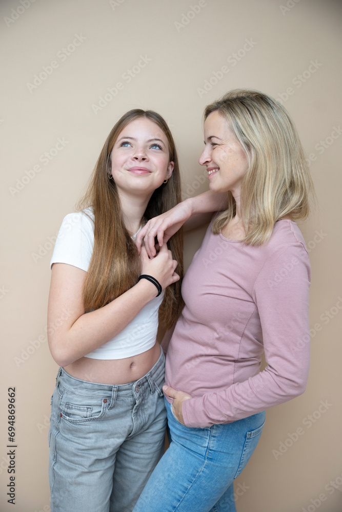 beautiful young, teenager girl together with her beautiful mother posing in front of brown background beautiful young, teenager girl together with her beautiful mother posing in front of brown background