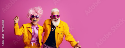 Cool retired hipsters, seniors party, carnival. Portrait of cheerful elderly gray-haired bearded grandparent wearing funny sunglasses and bright extravagant clothes on plain pink background