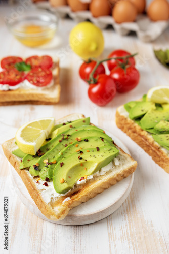 Sliced avocado on toast bread with spices on white wooden background. Food concept.