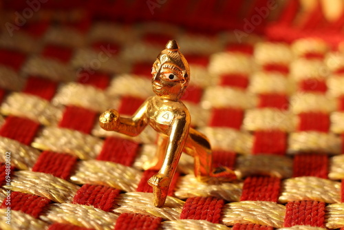 A shiny brass figurine of laddu Gopal or lord Krishna on a Check fabric pattern with background blur photo