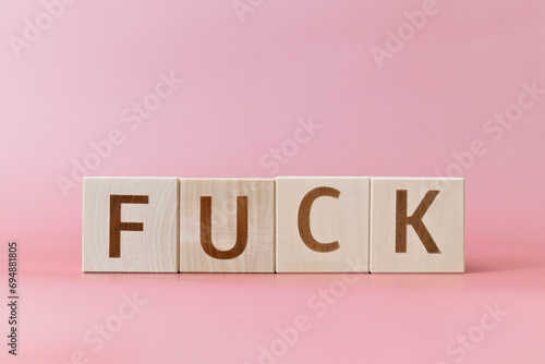 Indecent swear word on wooden cubes, close-up photo