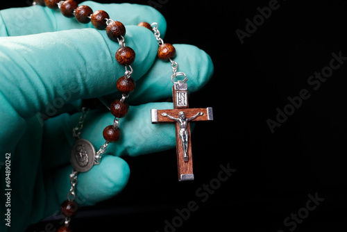 Coronavirus (COVID-19) epidemic, Christian praying rosary beads with protecting glove, France photo