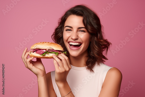 Young pretty brunette girl over isolated colorful background holding a sandwich