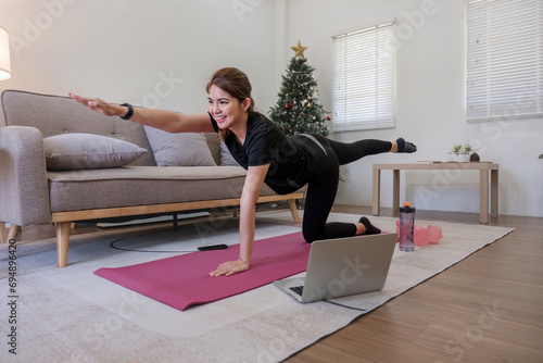Young Asian sporty fitness woman coach do practice video online training yoga laptop in living room at home