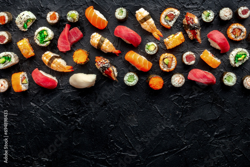 Sushi with a place for text. Many rolls, maki, nigiri etc, overhead flat lay composition on a black background, with copy space. Japanese sushi bar