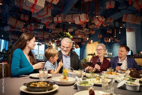 Overjoyed family sitting at table with glasses of wine celebrating Christmas