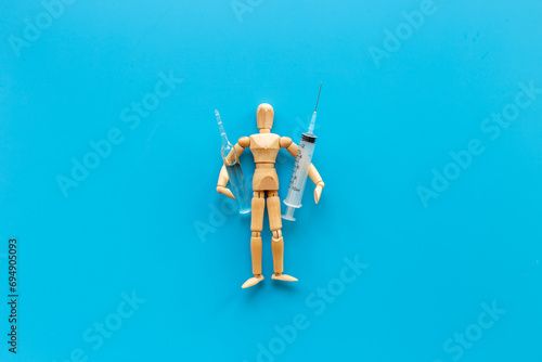 Wooden figurine of a man with syringe and vaccine. Medicine and healthcare concept