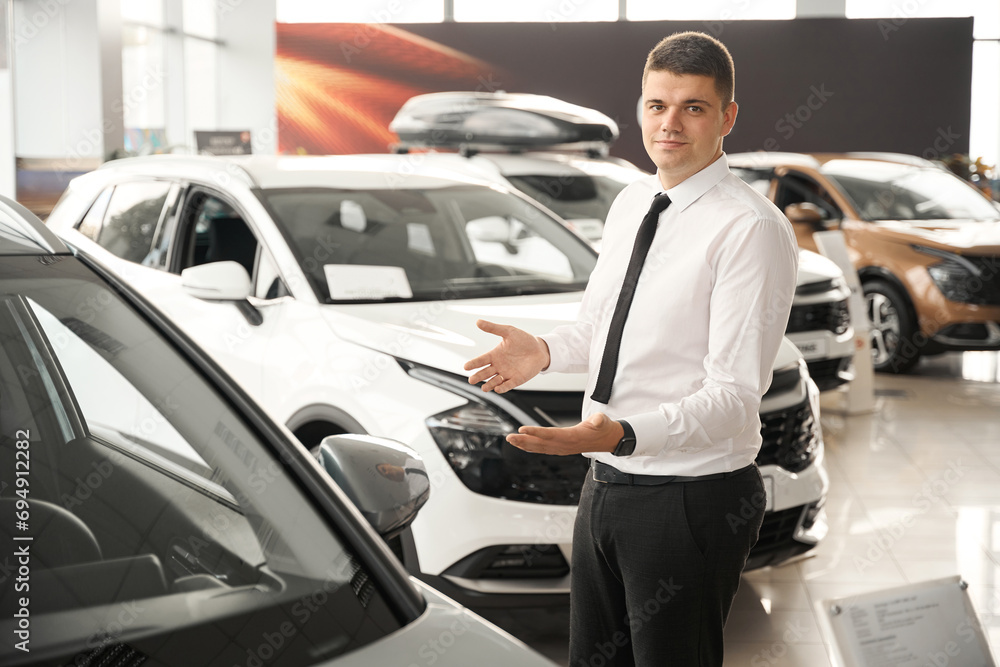 Auto salon manager offering new automobile for customers in modern dealership