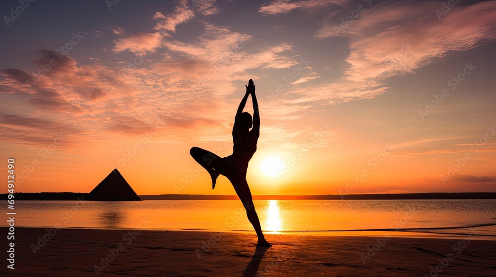 A silhouette of a woman in the Extended Triangle Pose (Utthita Trikonasana) on a beach during sunset