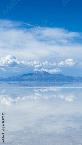 Uyuni Salt Flats. Altiplano, Bolivia. Rainy Season. Tunupa Volcano. Clouds Reflection on Water in Lake Surface. Time Lapse. Vertical Video photo