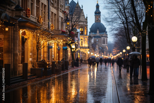 Twilight scene of pedestrians walking on a wet city street adorned with festive lights, reflecting on the pavement.