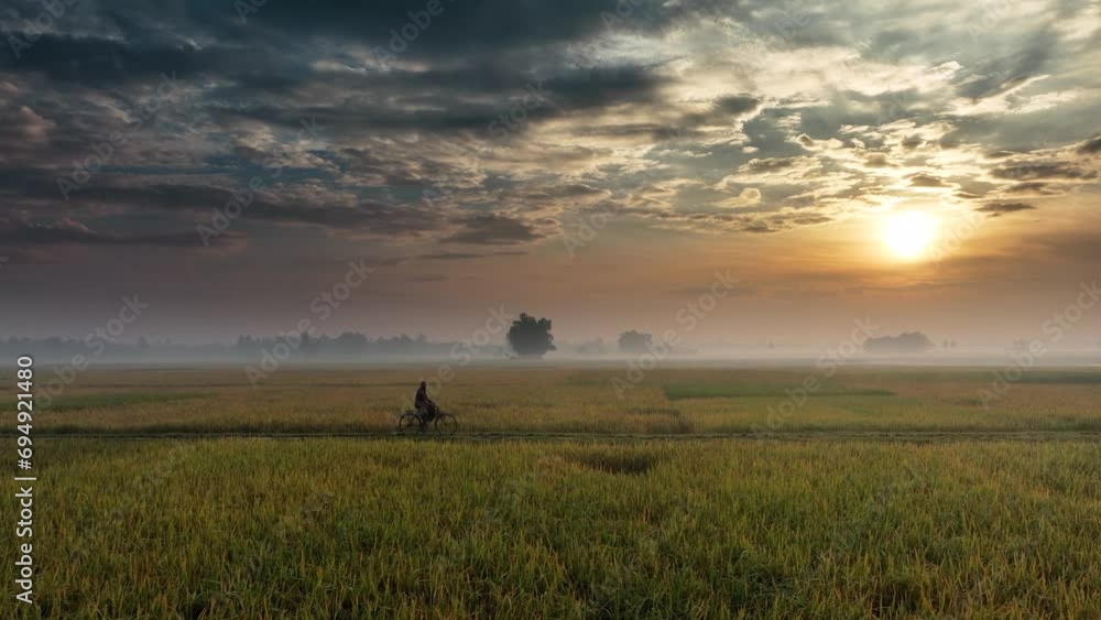 A lone cyclist navigates through this tranquil landscape while clouds drift and the sun sets in a stunning display of colors in the western sky. Witness nature's serene canvas in motion, a picturesque A lone cyclist navigates through this tranquil landscape while clouds drift and the sun sets in a stunning display of colors in the western sky. Witness nature's serene canvas in motion, a picturesque
