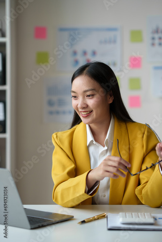 Cheerful businesswoman working with laptop in office, chatting Look at the laptop and talk about business, marketing, presentations video conference call meeting online training working in the office photo