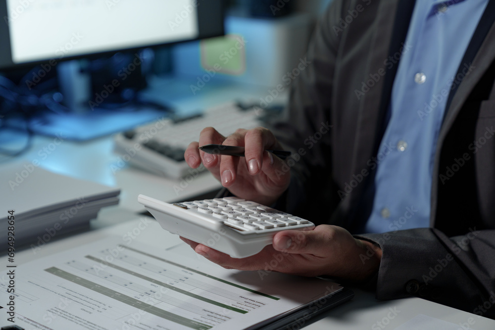 Young Asian businessman uses a calculator to analyze financial data, marketing, balance sheets, net profits, taxes to plan sales strategies. Calculate the company's budget business management concept Young Asian businessman uses a calculator to analyze financial data, marketing, balance sheets, net profits, taxes to plan sales strategies. Calculate the company's budget business management concept