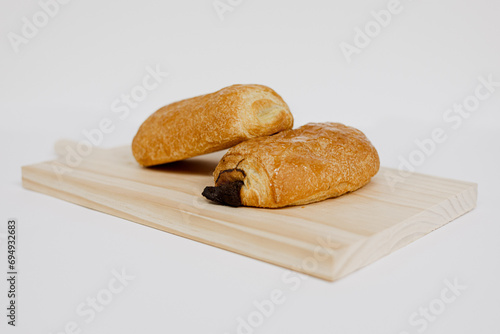 Napolitanas de chocolate y crema en una tabla de madera sobre fondo blanco. Fotografía de producto de panadería