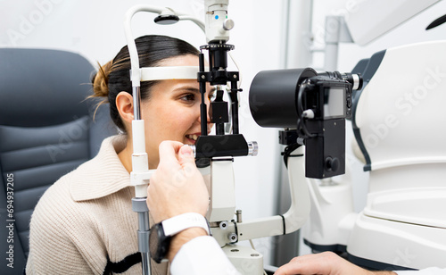 An unrecognizable ophthalmologist uses a slit lamp with a camera to examine a woman's eye. Biomicroscope.Eye health concept. Observation of the surface of the anterior pole of the eyeball