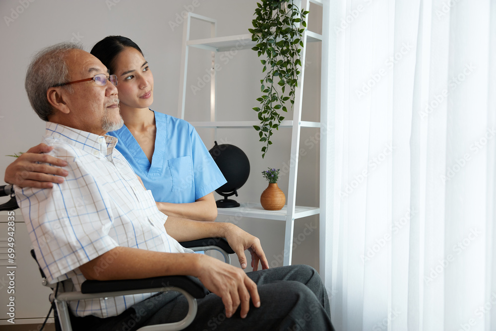 nurse or caregiver beside elderly man sitting on wheelchair and looking outside at home nurse or caregiver beside elderly man sitting on wheelchair and looking outside at home