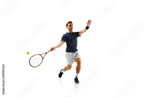 Young athletic man, tennis player in motion, hitting ball with racket isolated over white background. Dynamic game. Concept of professional sport, competition, game, math, hobby, action