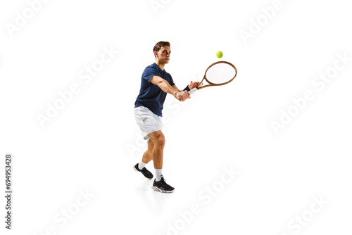 Young athletic man, tennis player in motion, hitting ball with racket isolated over white background. Dynamic game. Concept of professional sport, competition, game, math, hobby, action © master1305
